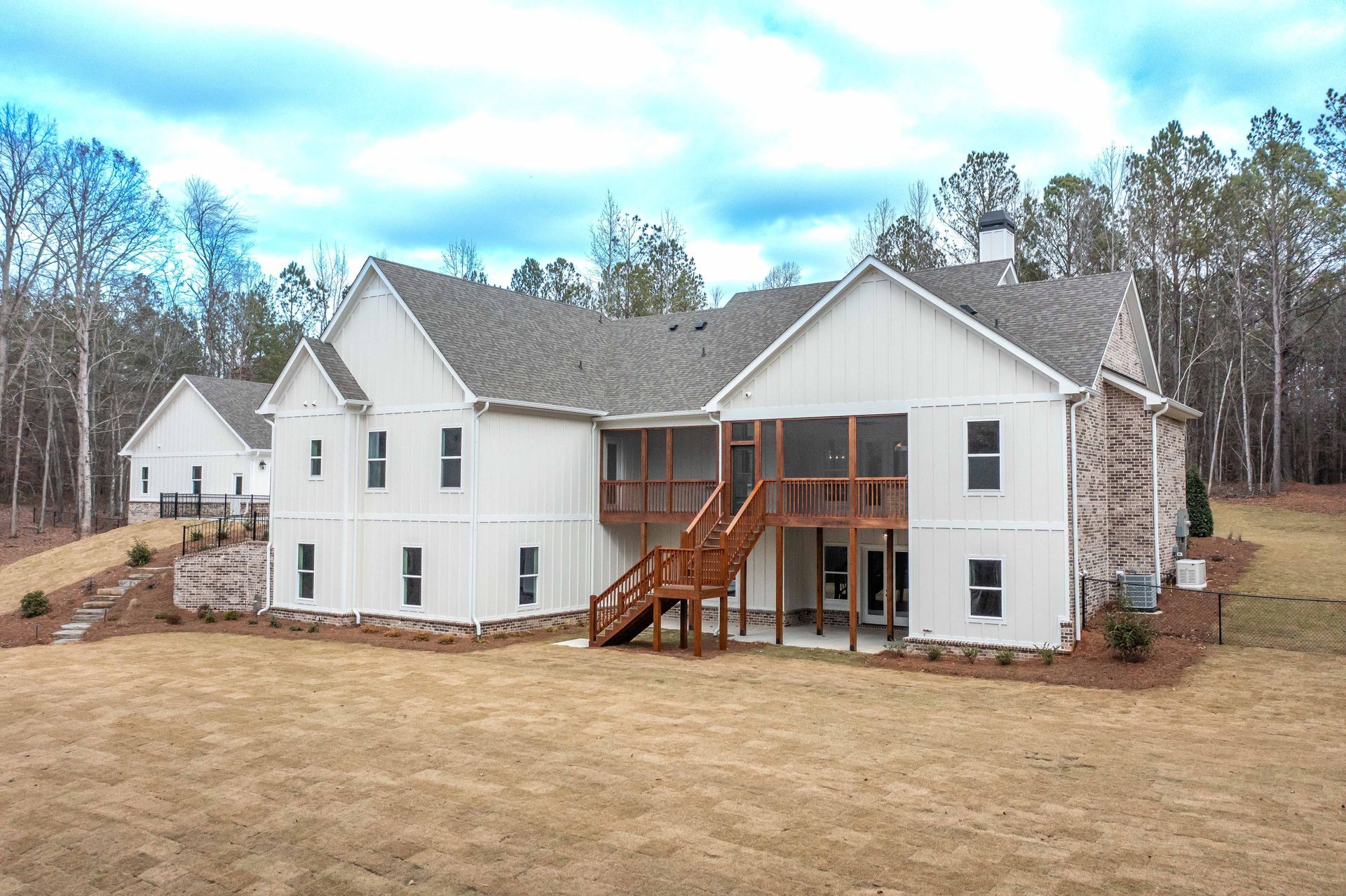The back of a large white house with a screened in porch.