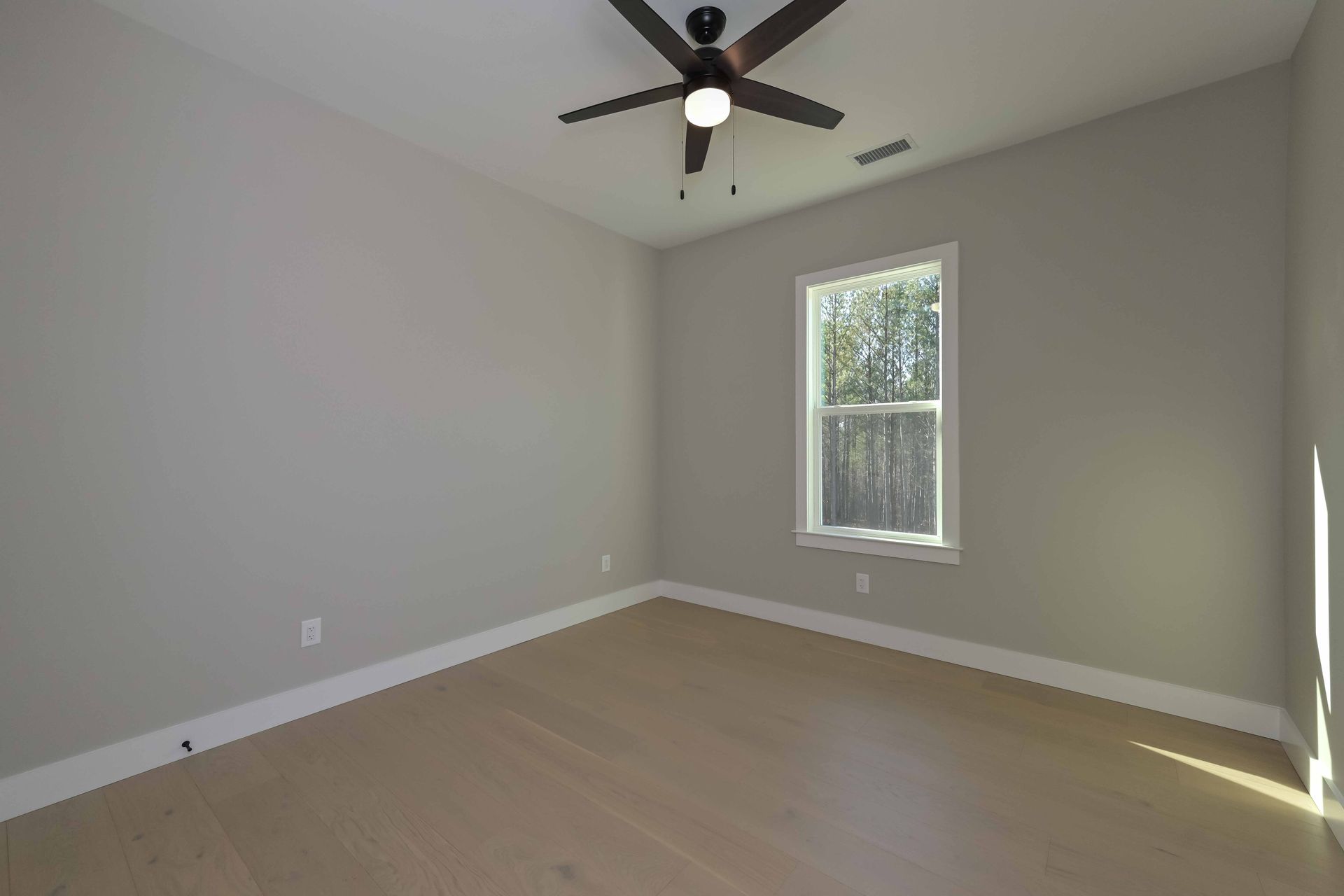 An empty bedroom with a ceiling fan and a window.