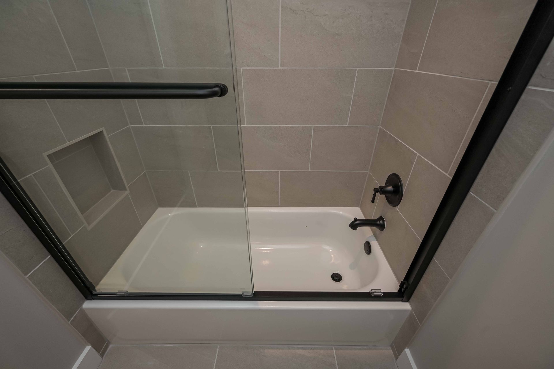 A bathtub in a bathroom with a glass shower door.