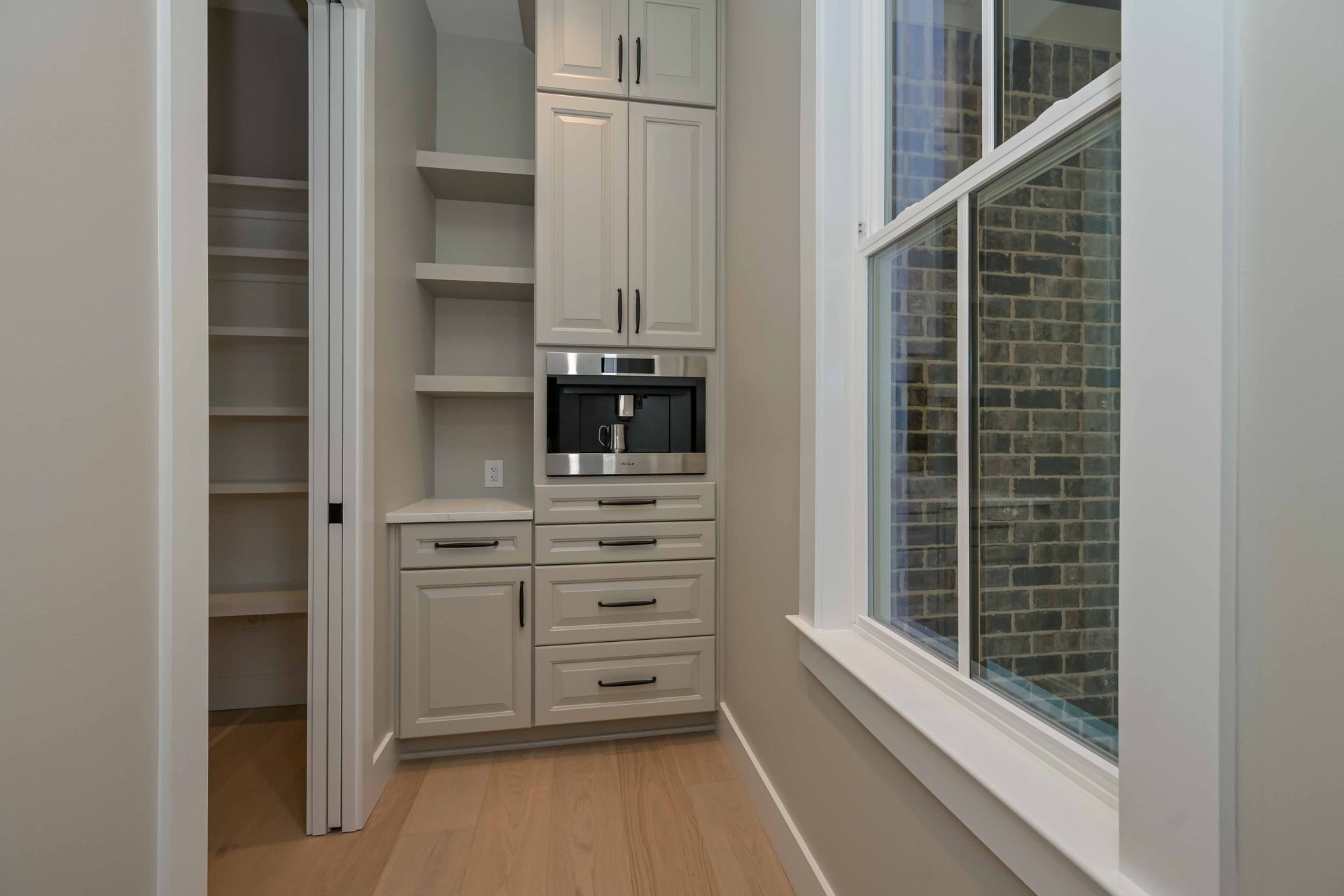A kitchen with white cabinets , stainless steel appliances and a window.