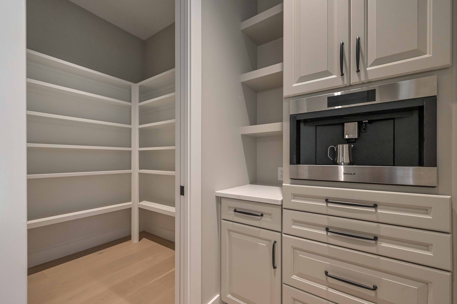 A kitchen with white cabinets , stainless steel appliances , and a coffee maker.