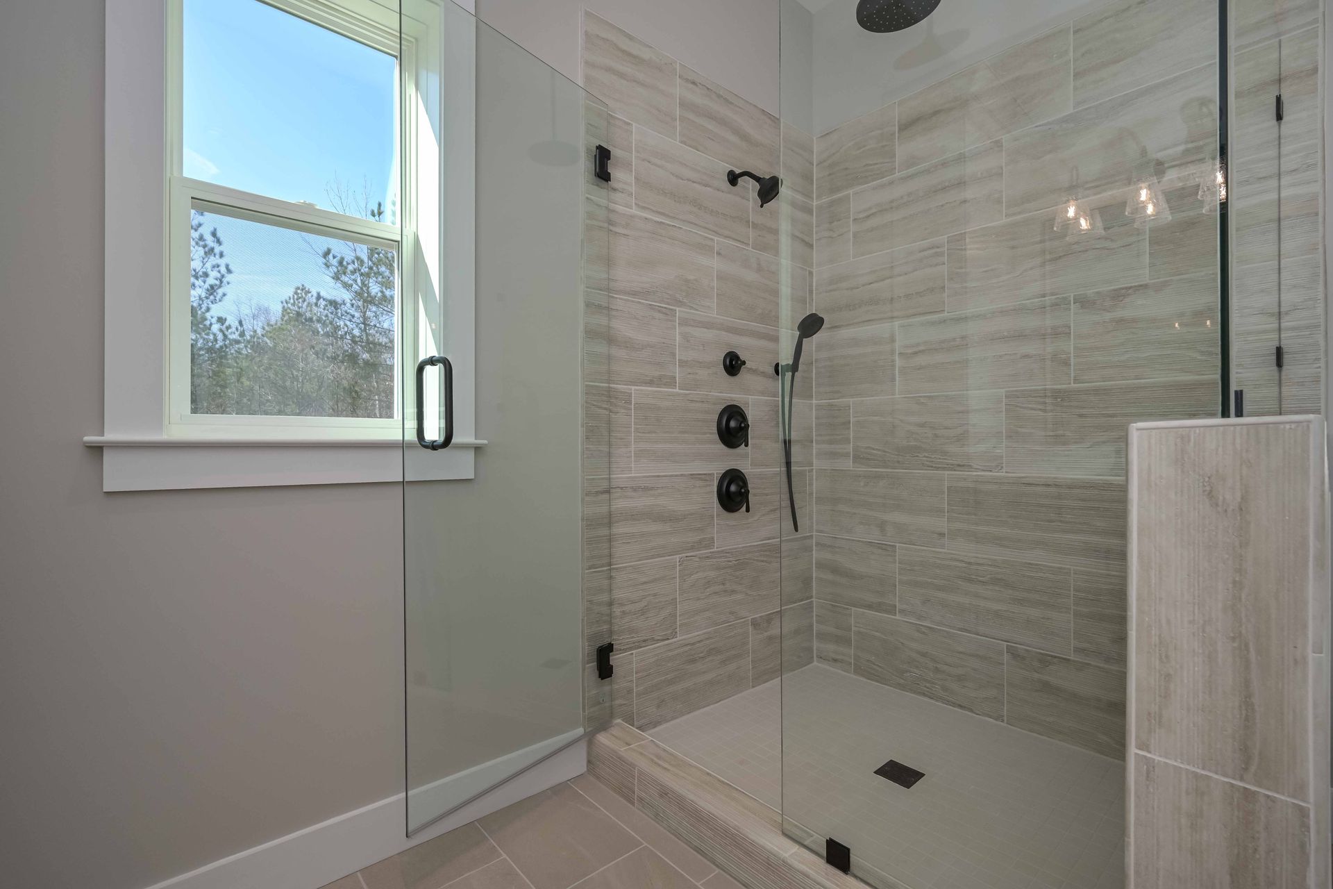 A bathroom with a walk in shower and a window.
