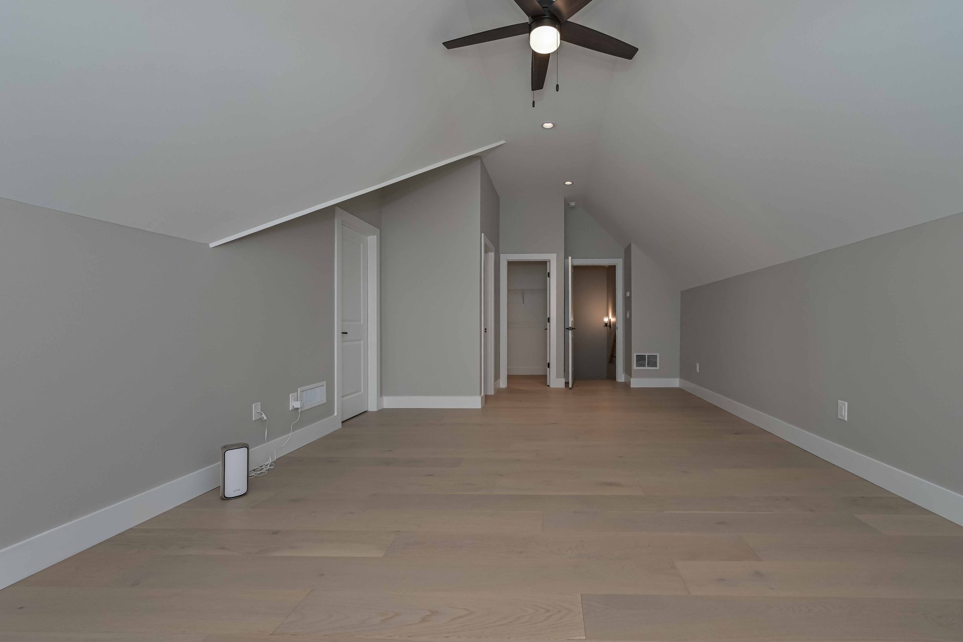 An empty room with hardwood floors and a ceiling fan.