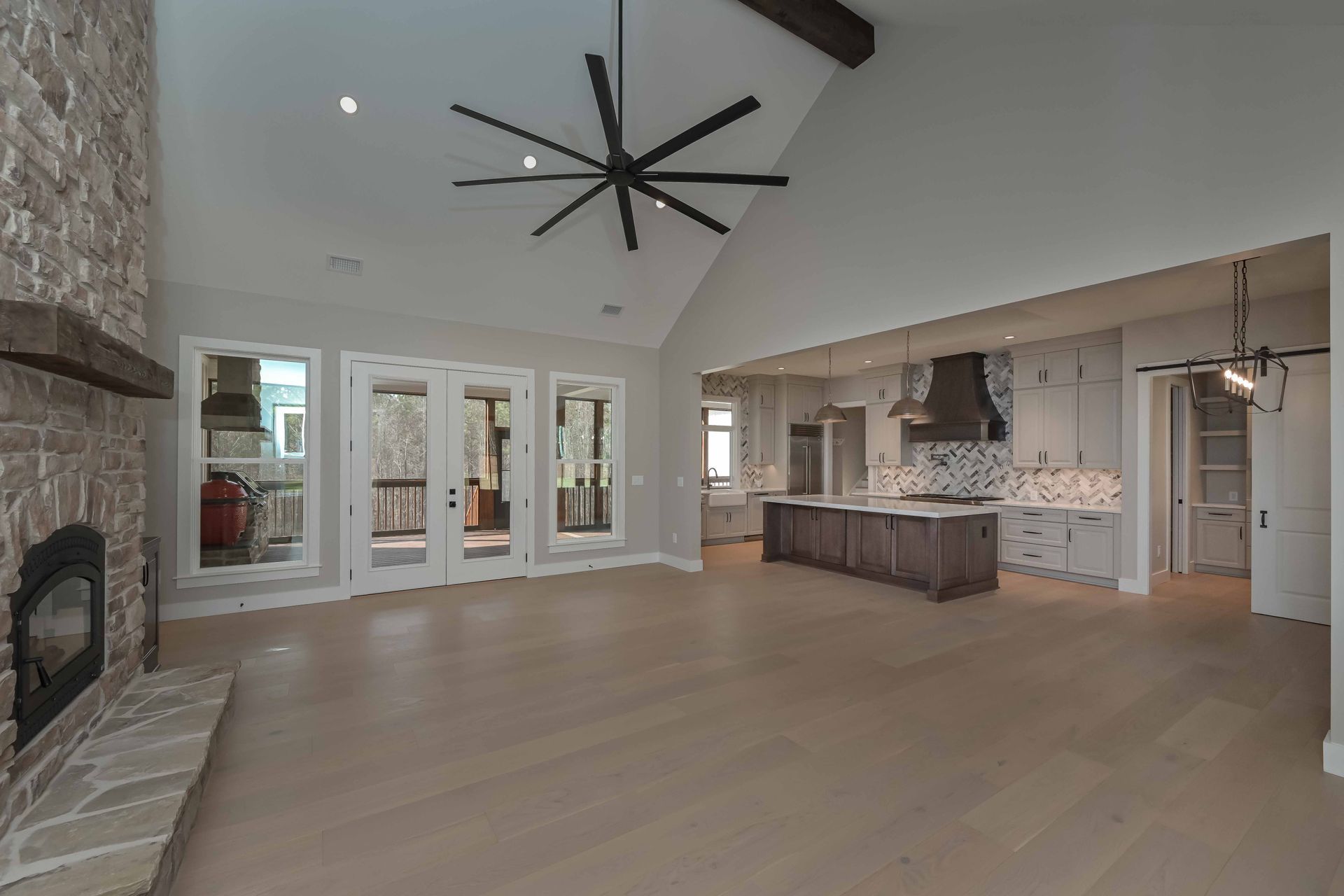 A large empty living room with a ceiling fan and a fireplace.
