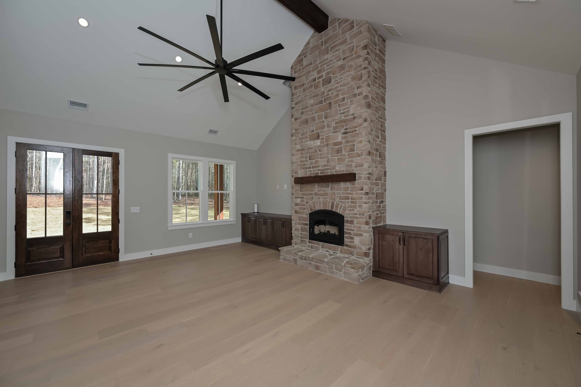 An empty living room with a fireplace and a ceiling fan.