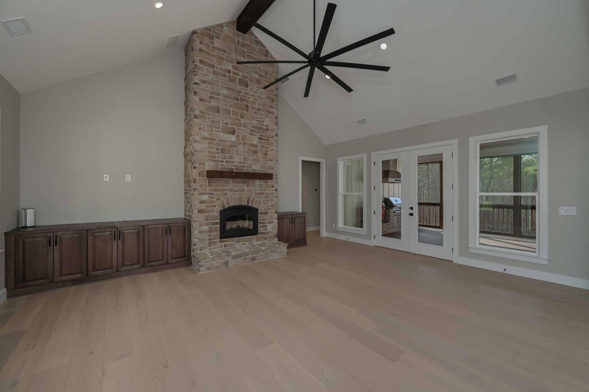 An empty living room with a fireplace and a ceiling fan.