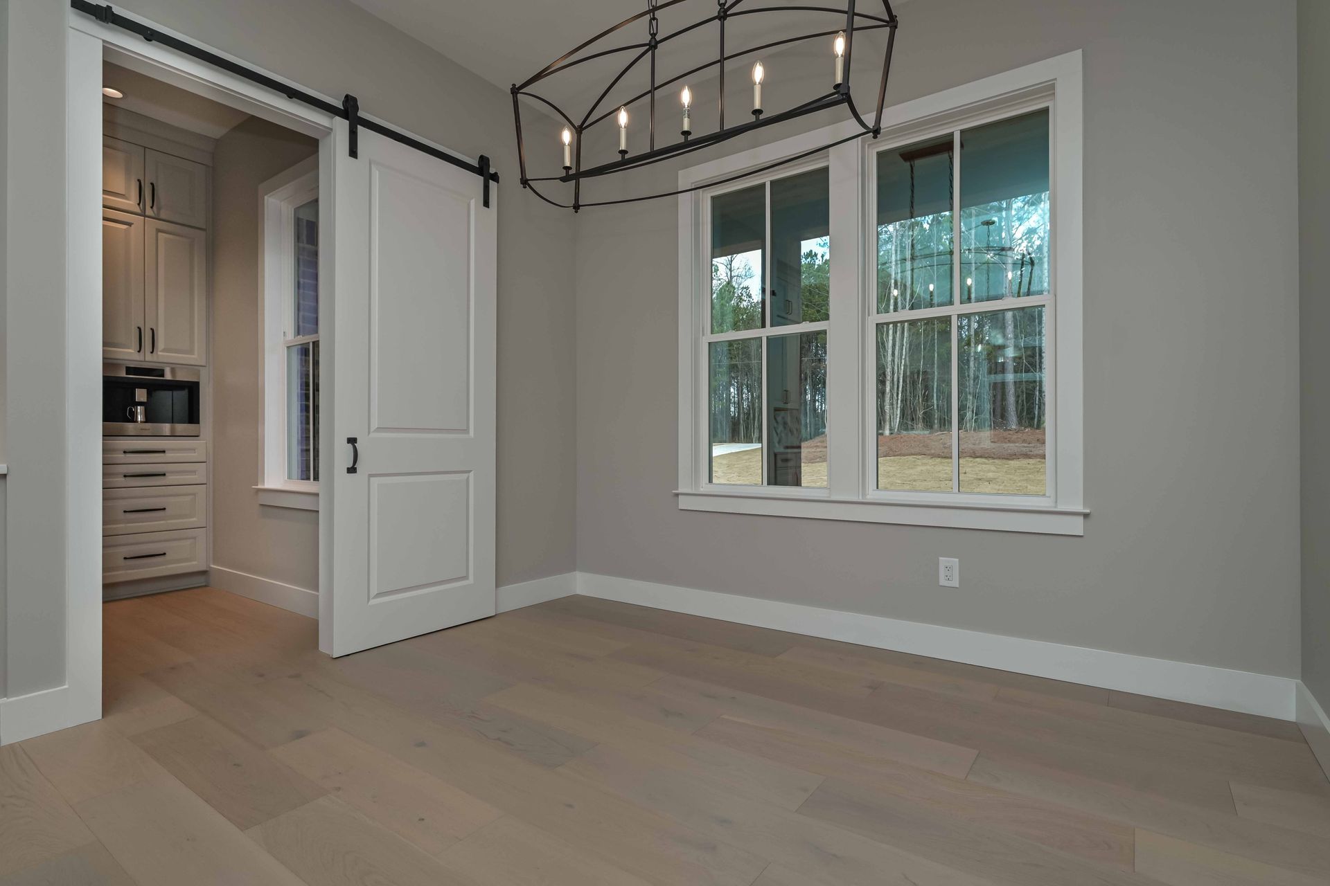 An empty room with sliding barn doors and a chandelier.