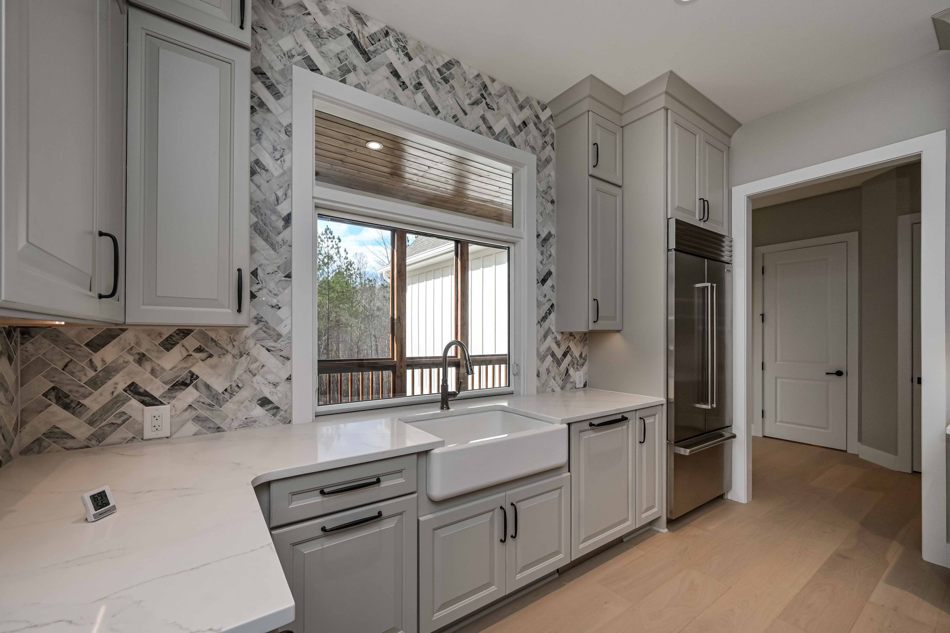 A kitchen with white cabinets , stainless steel appliances , a sink , and a large window.