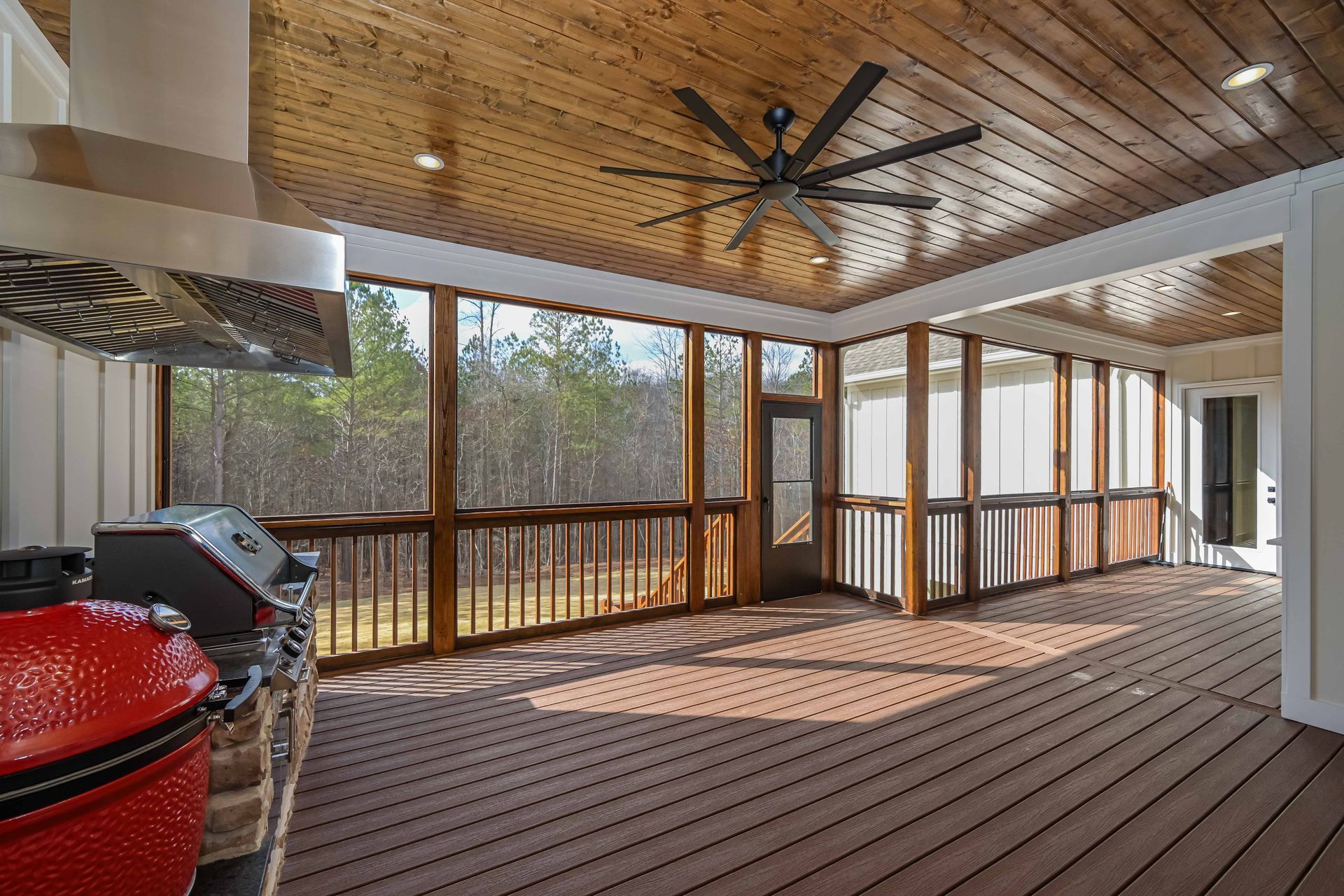 A screened in porch with a grill and ceiling fan.
