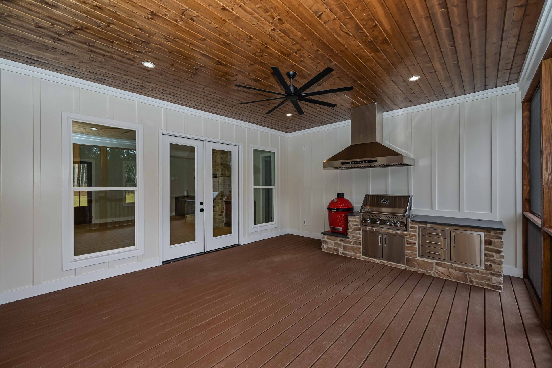 A covered patio with a grill and a ceiling fan.