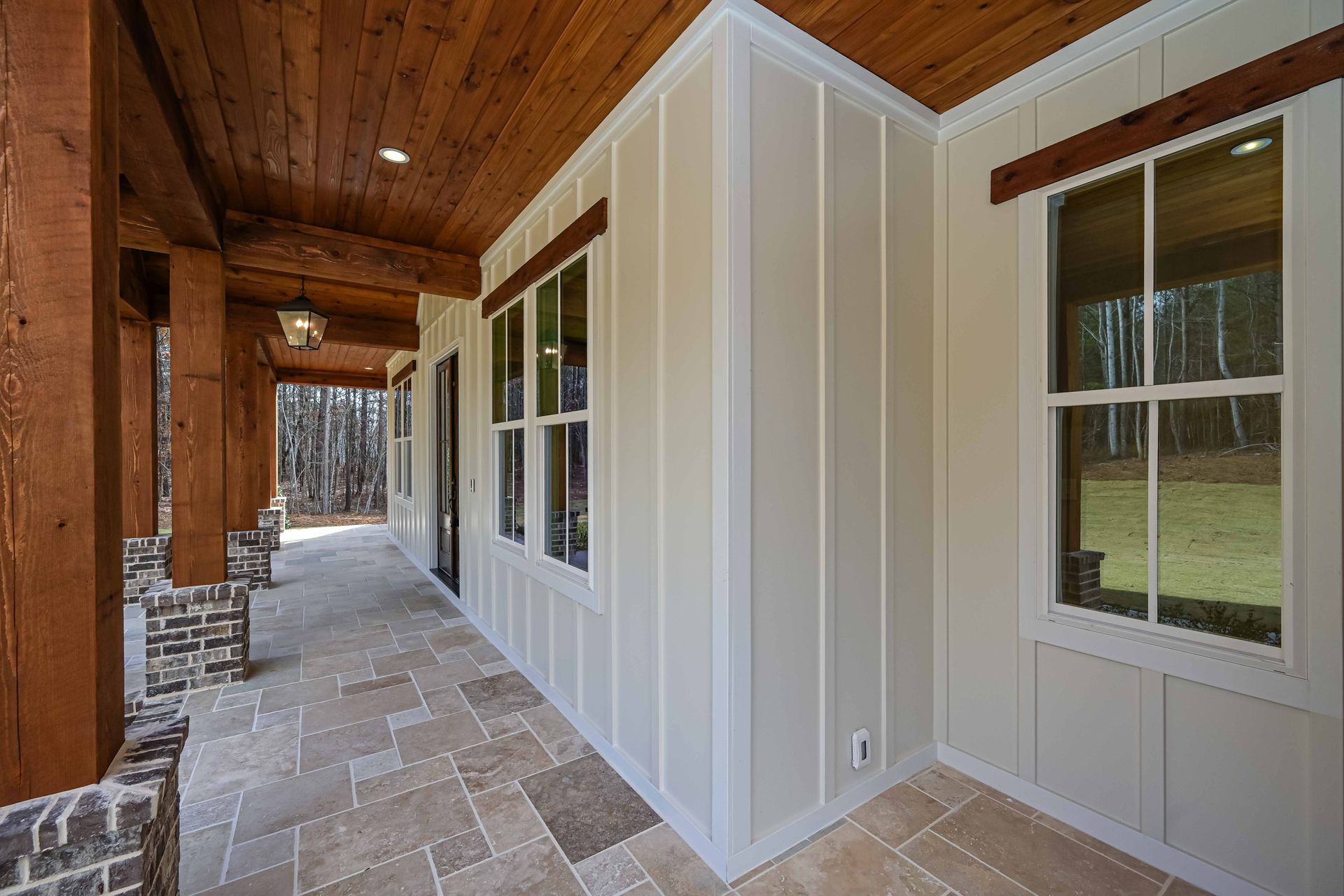 A long porch with a wooden ceiling and a lot of windows.