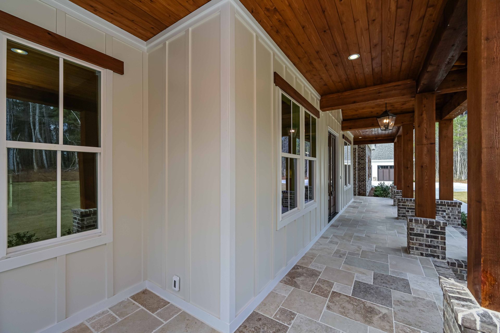 There is a porch with a wooden ceiling and a lot of windows.