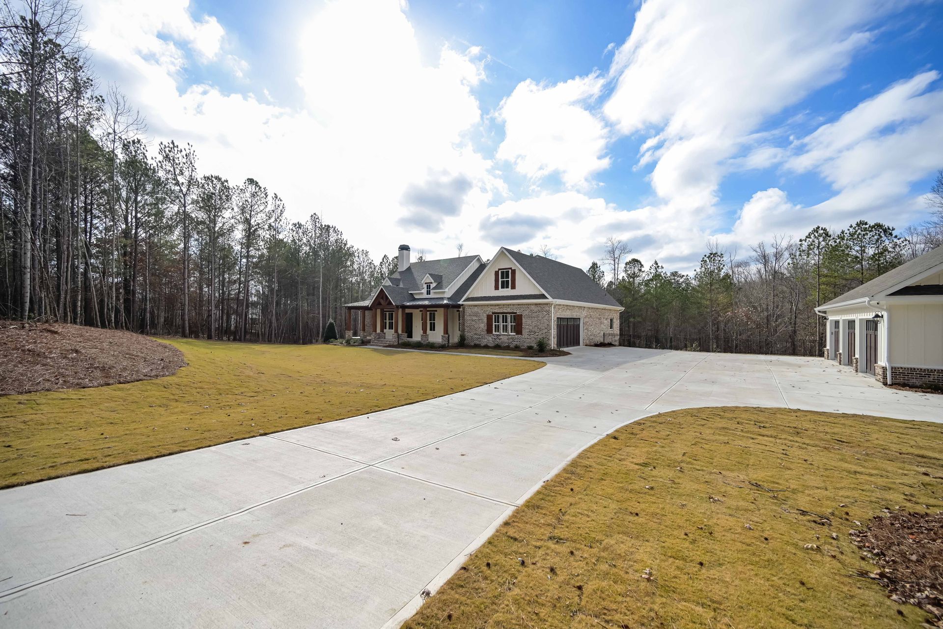 A driveway leading to a house with trees in the background