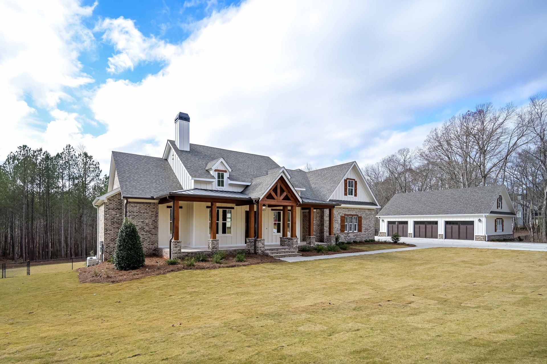 A large white house with a gray roof is sitting in the middle of a grassy field.