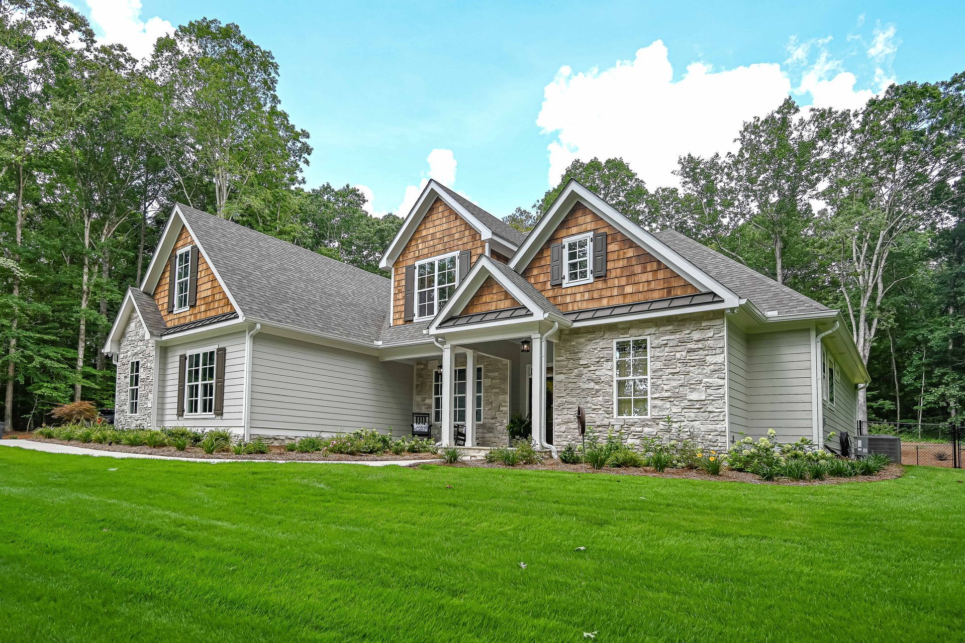 A large house with a large lawn in front of it is surrounded by trees.