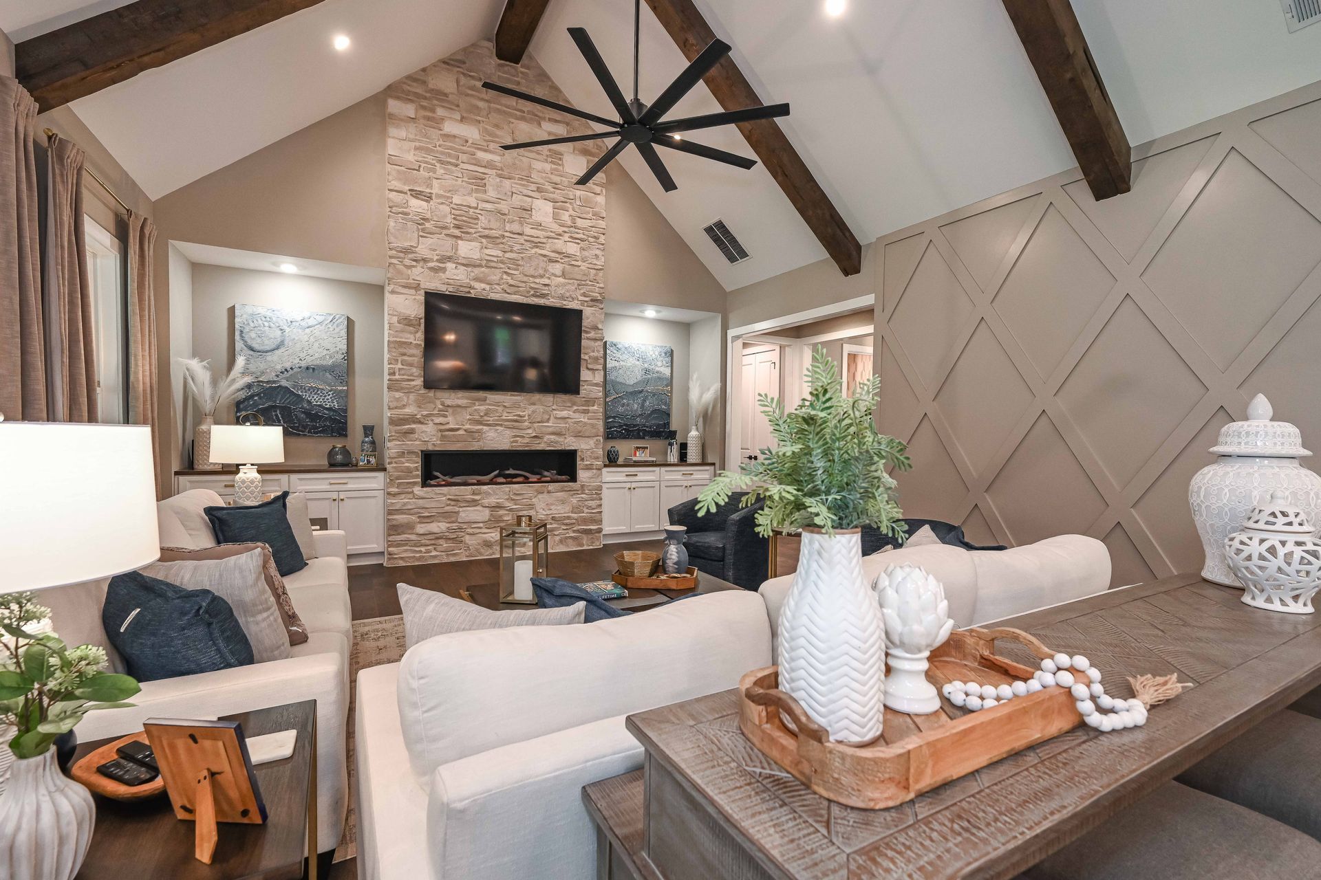 A living room with a couch , chairs , a table and a ceiling fan.