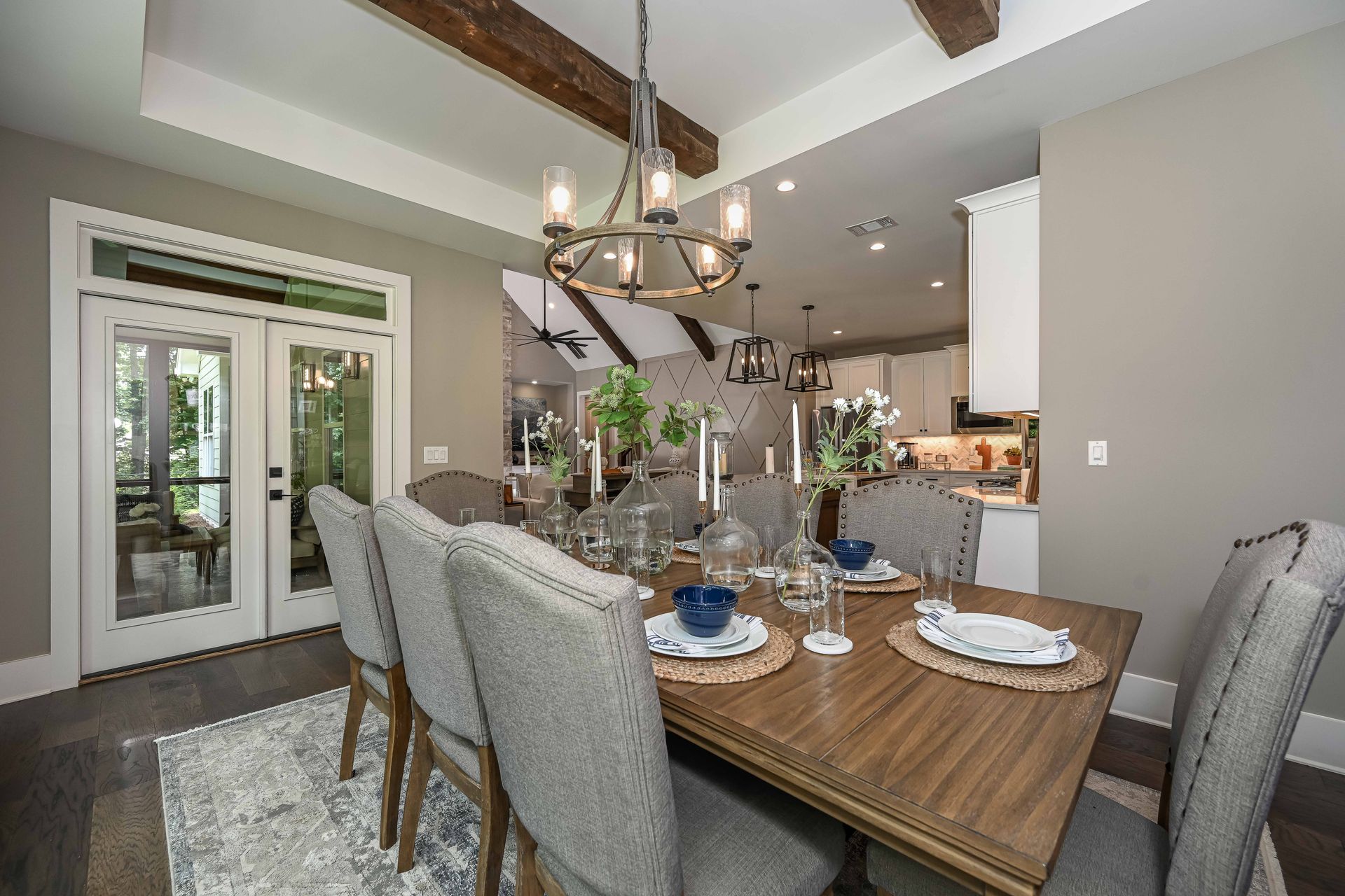 A dining room with a wooden table and chairs and a chandelier.