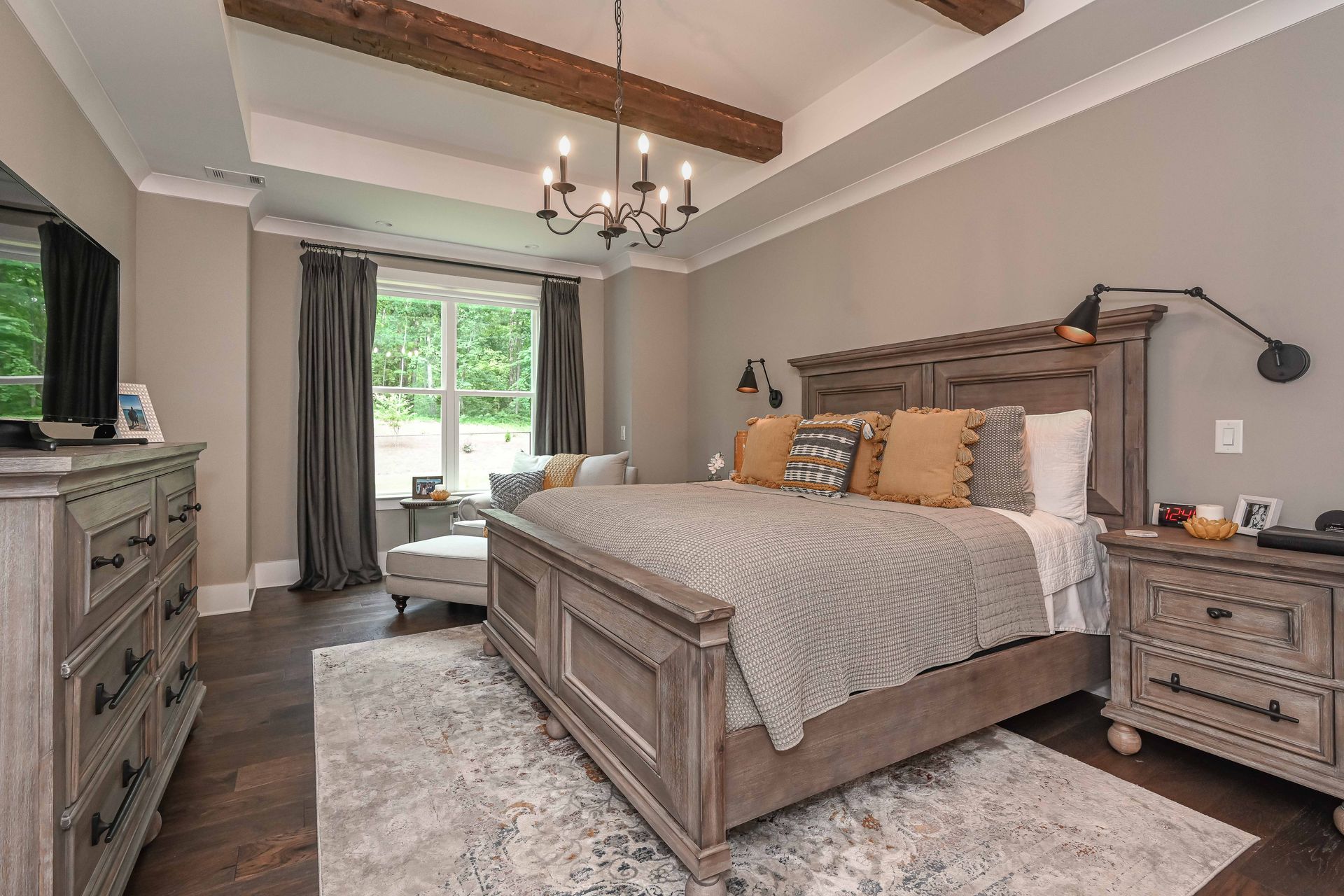 A bedroom with a large bed , dresser , nightstand and television.