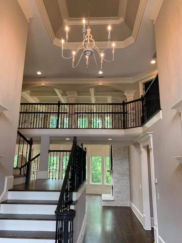 A large hallway with stairs and a chandelier hanging from the ceiling