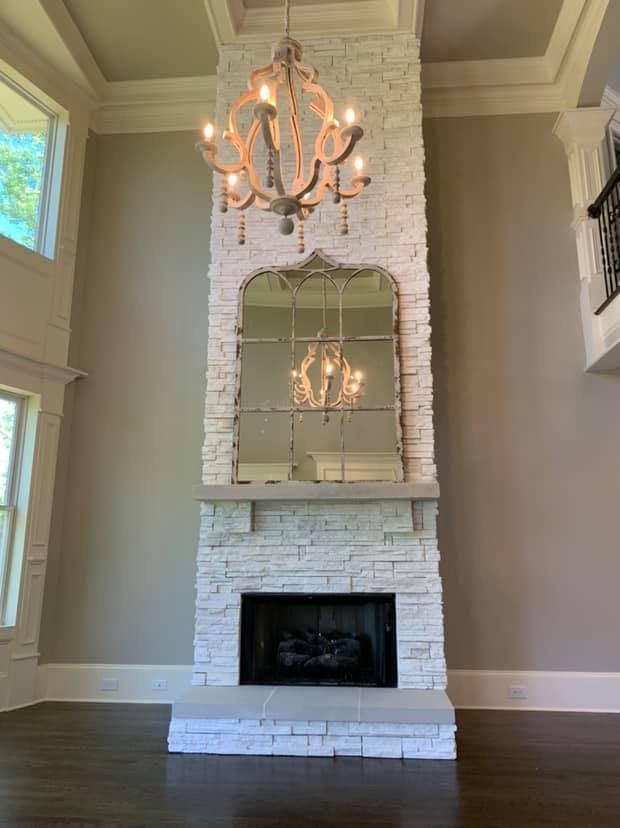 A living room with a fireplace , mirror and chandelier