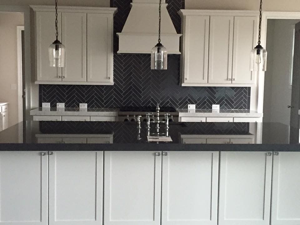 A kitchen with white cabinets and black counter tops