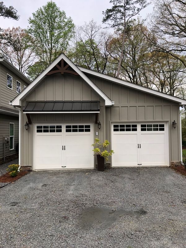 A garage with two white garage doors is sitting next to a house