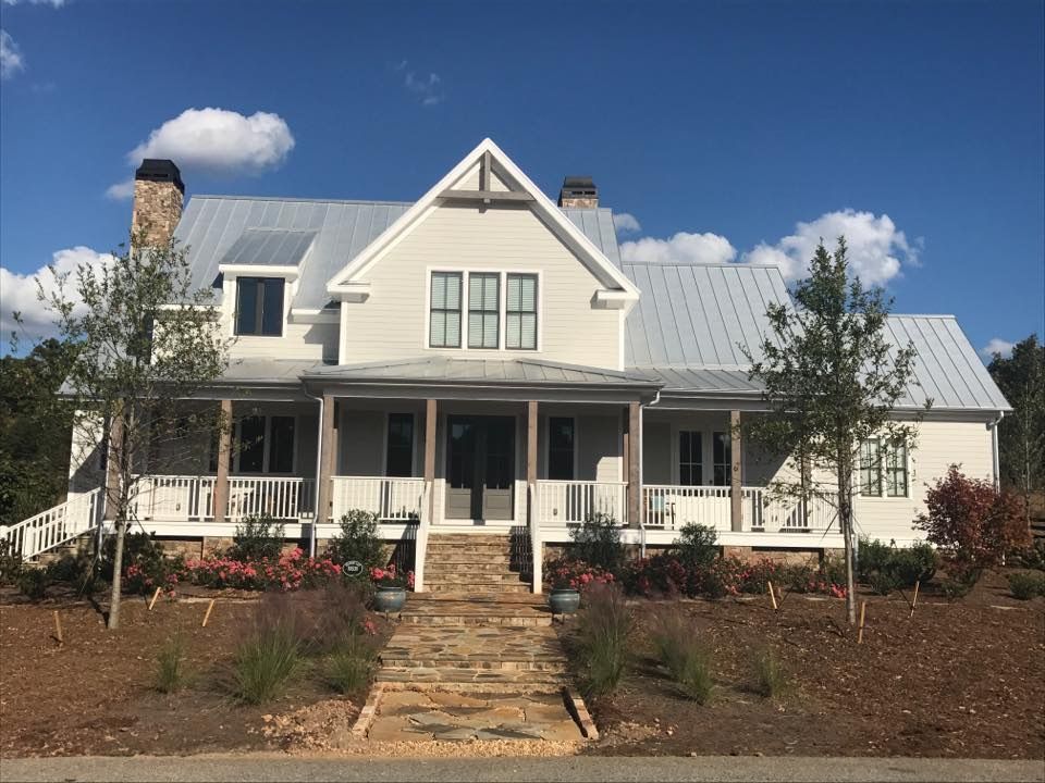 A large white house with a metal roof and a large porch