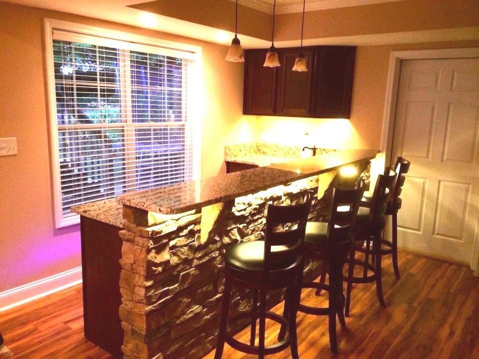 A kitchen with a bar and stools and a window