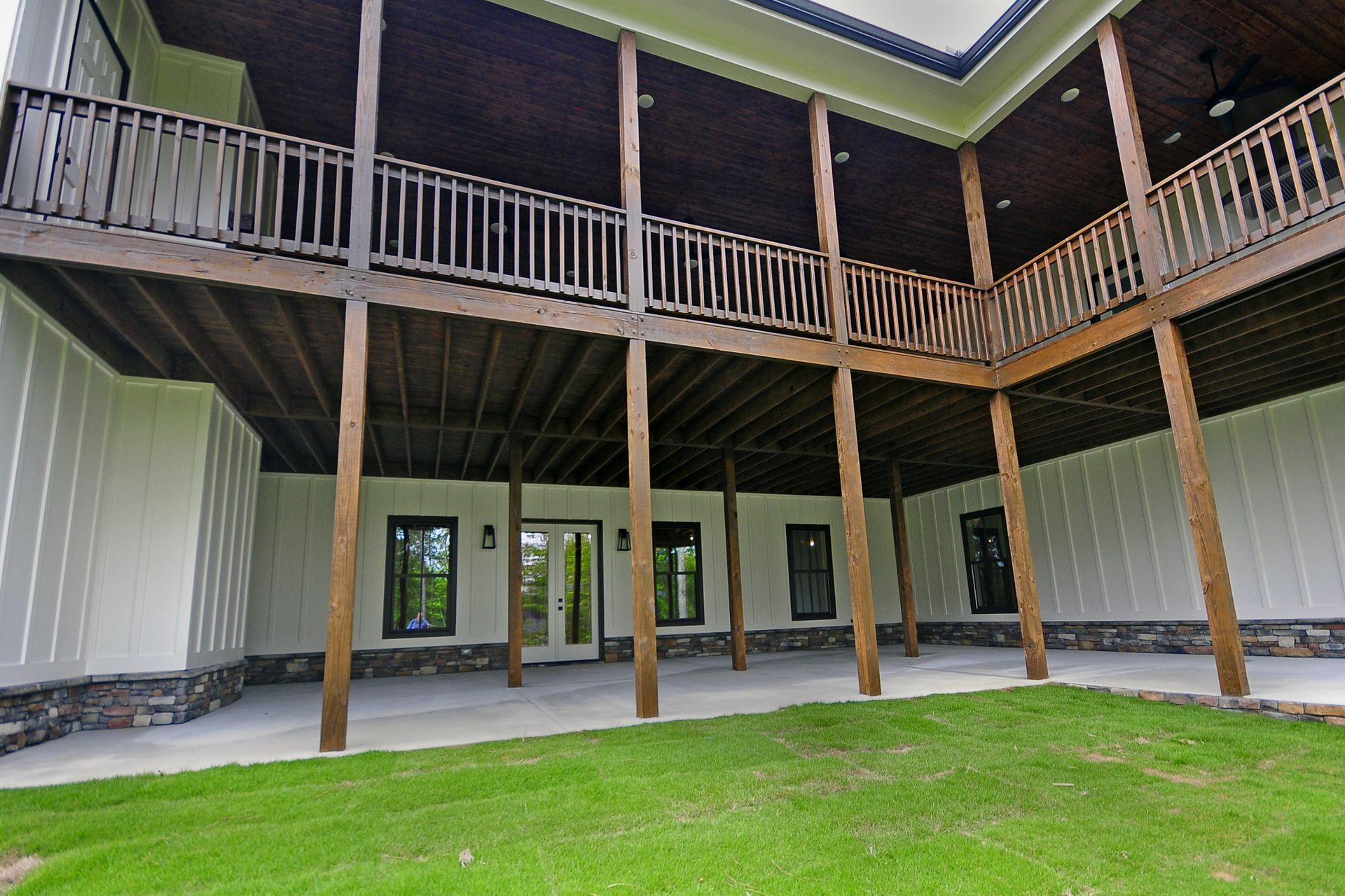 A large house with a large deck and a lawn in front of it