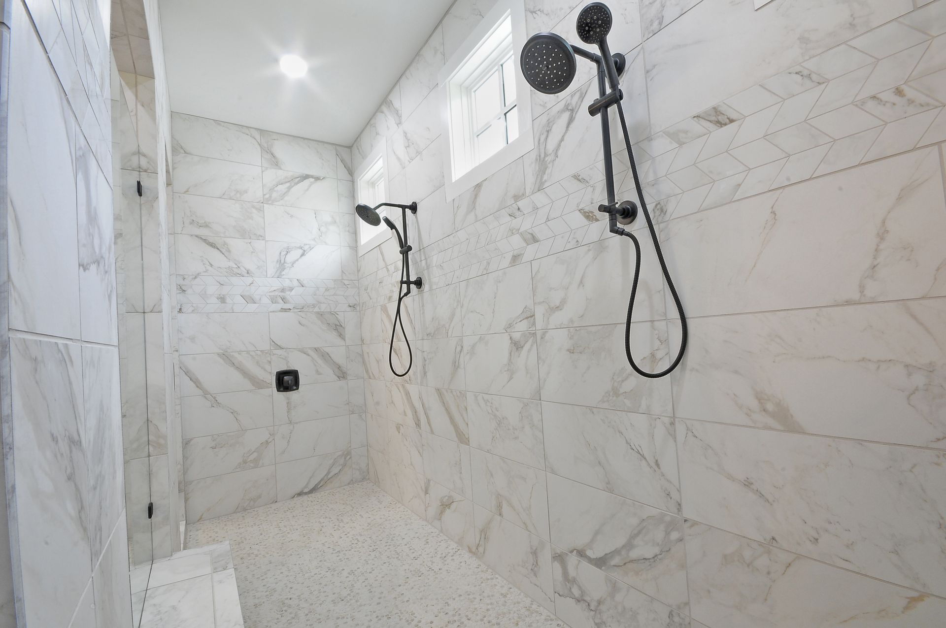A large walk in shower with marble tiles and two shower heads.