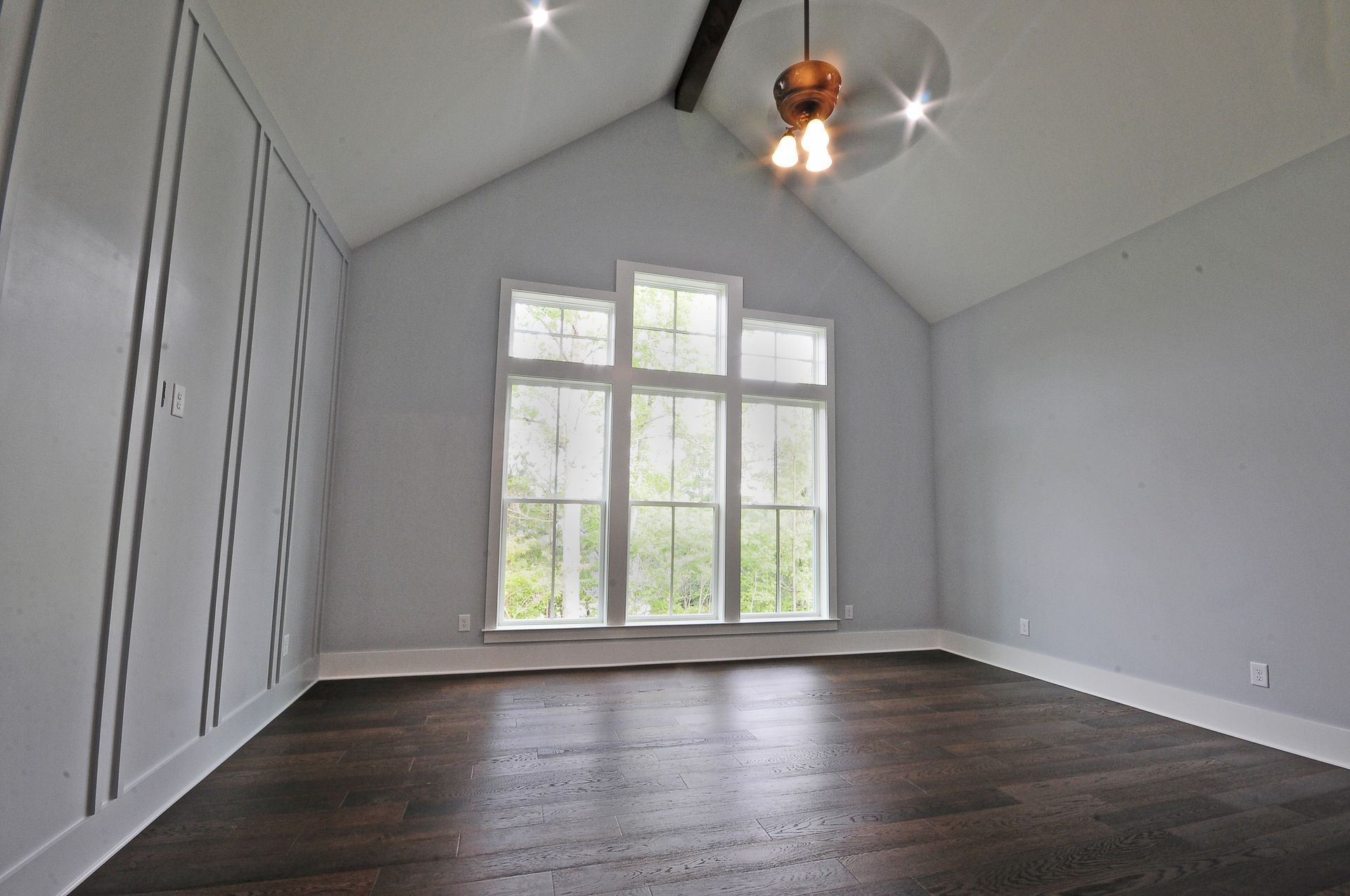 An empty room with a vaulted ceiling and a ceiling fan.