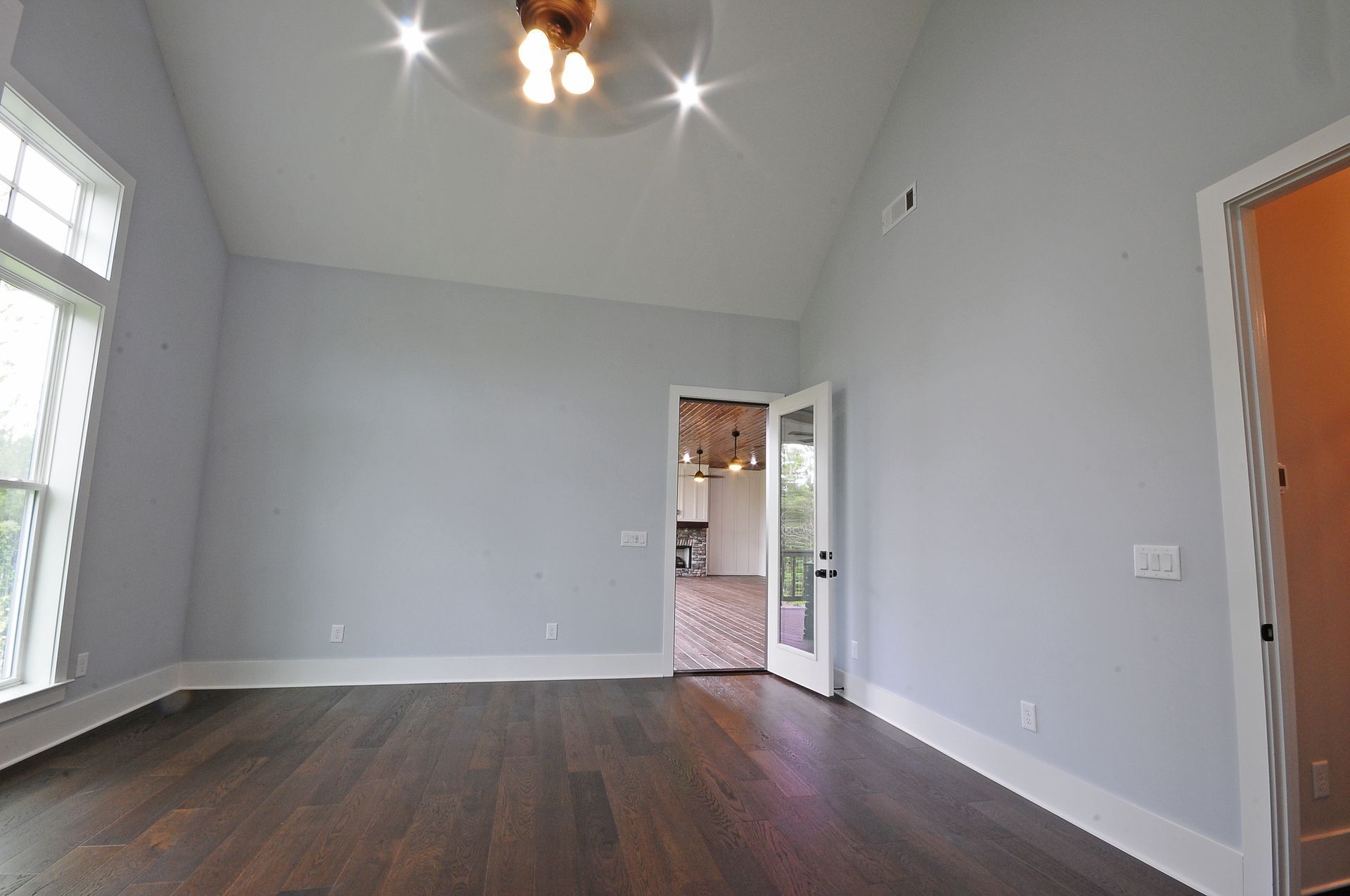 An empty living room with hardwood floors and a ceiling fan.
