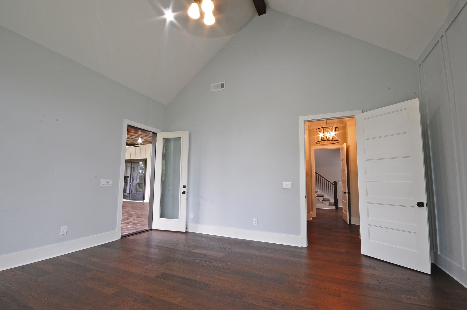 An empty room with a vaulted ceiling and hardwood floors