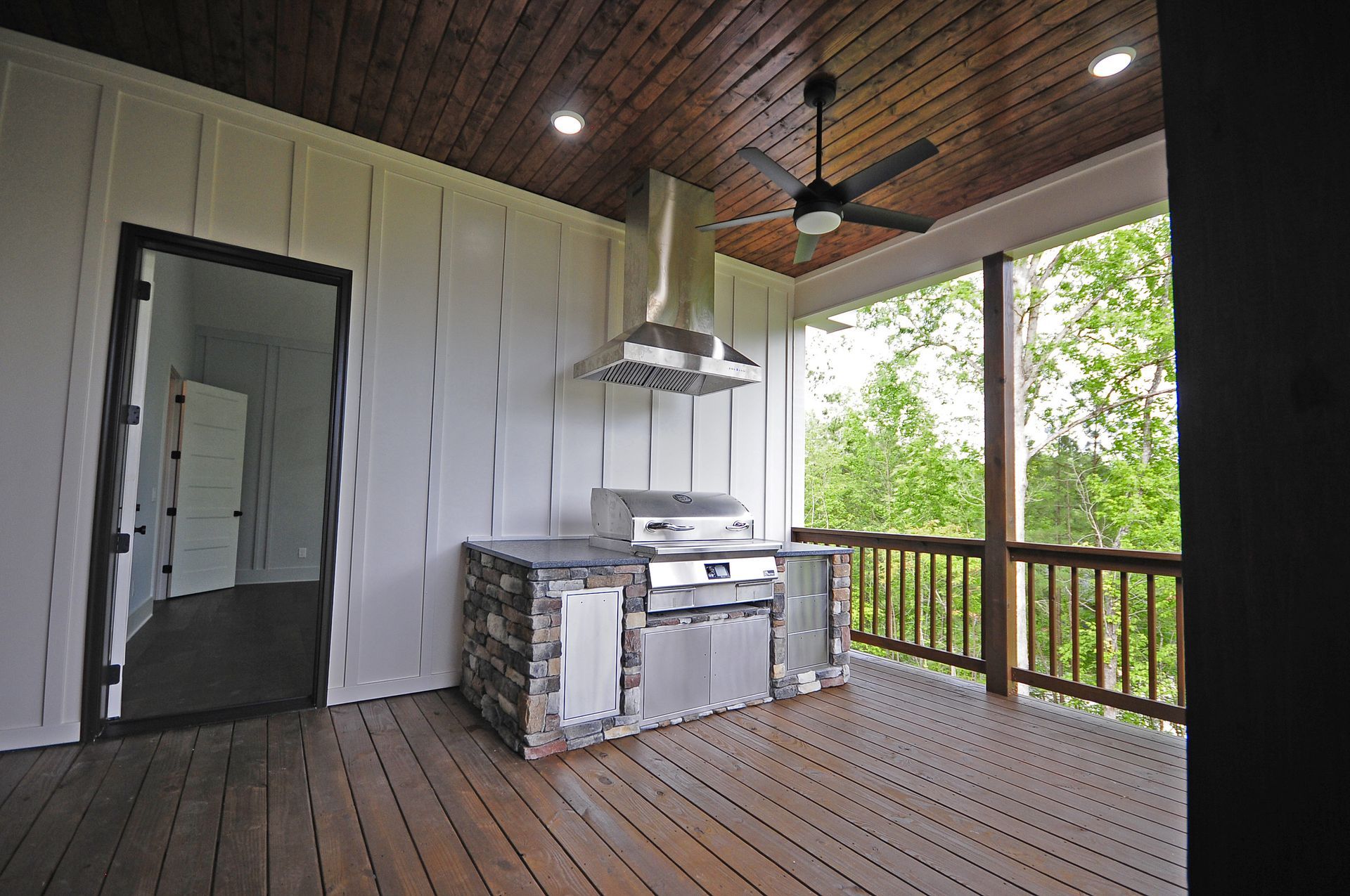 A porch with a grill and a ceiling fan
