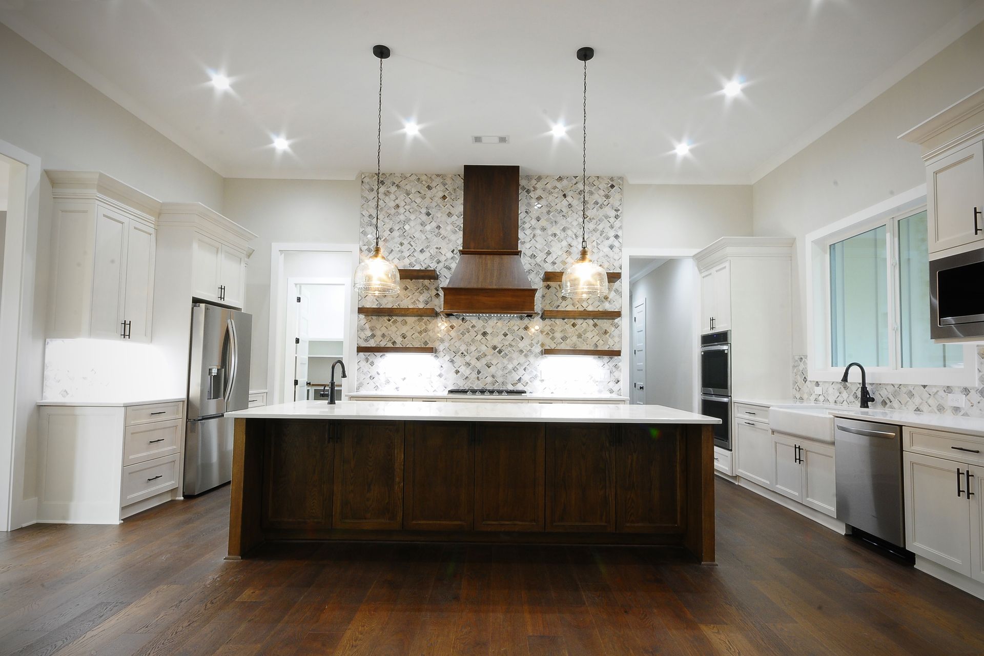 A large kitchen with a large island in the middle and stainless steel appliances.
