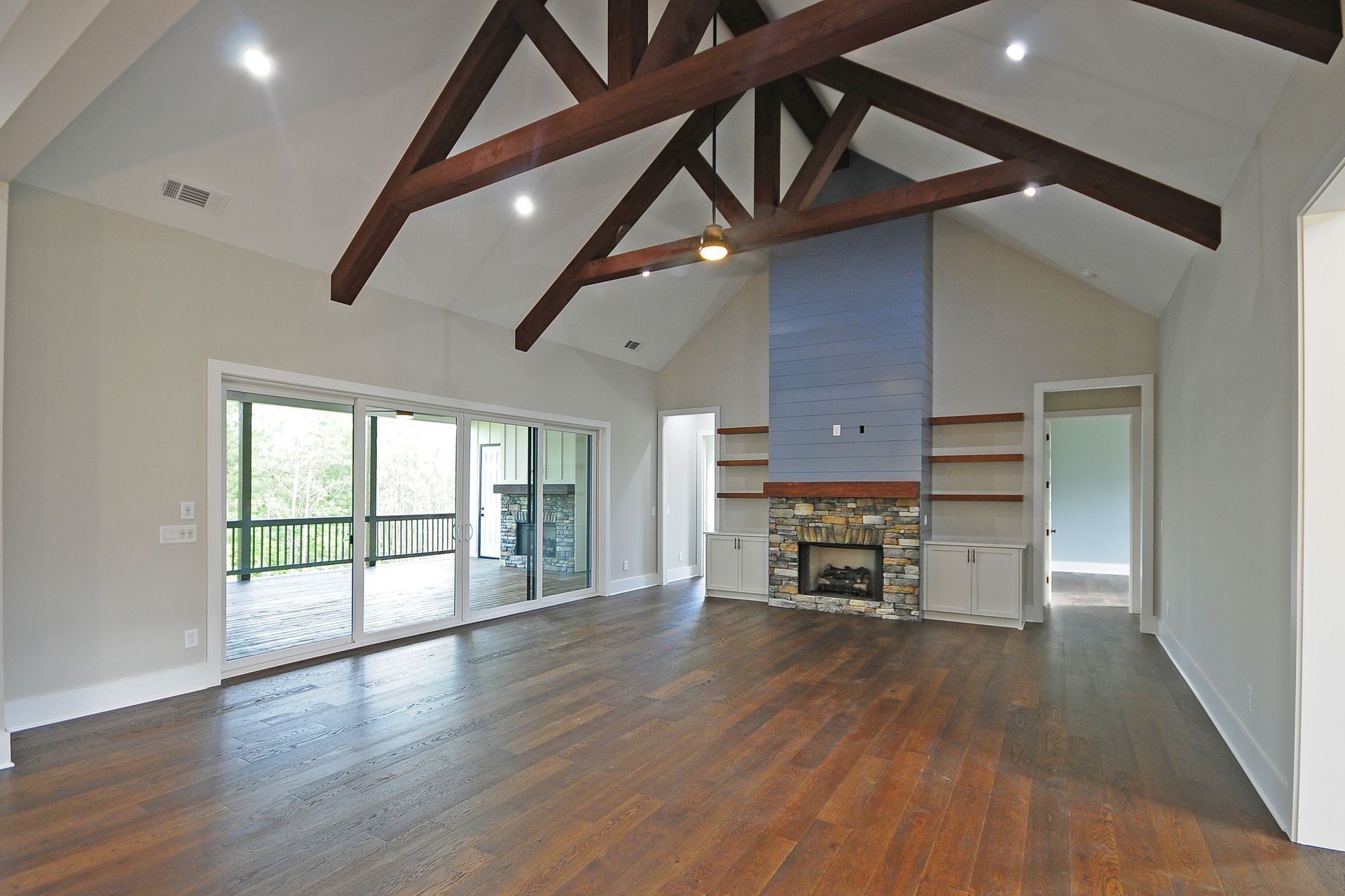 An empty living room with a fireplace and sliding glass doors