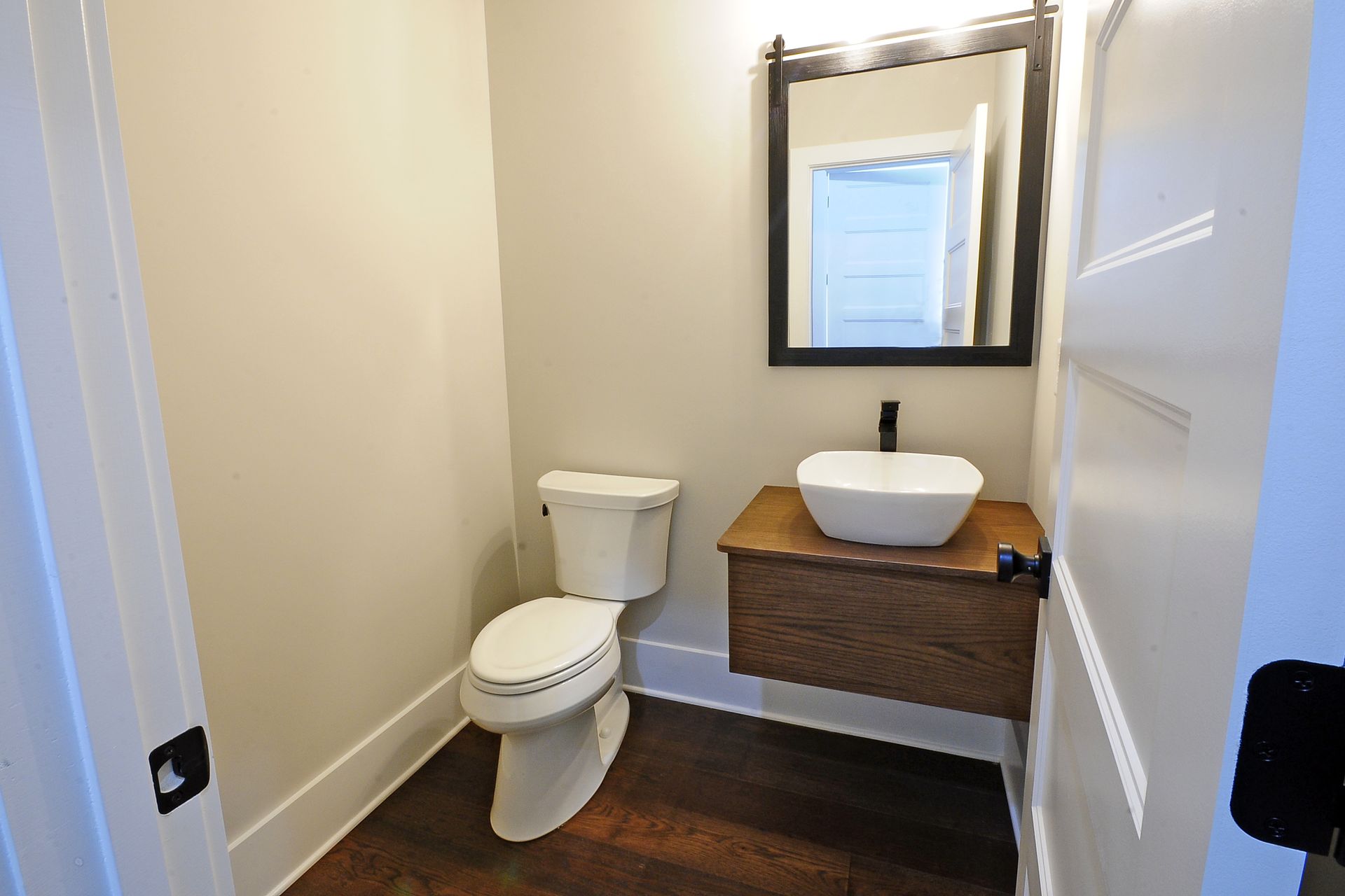 A bathroom with a toilet , sink and mirror.