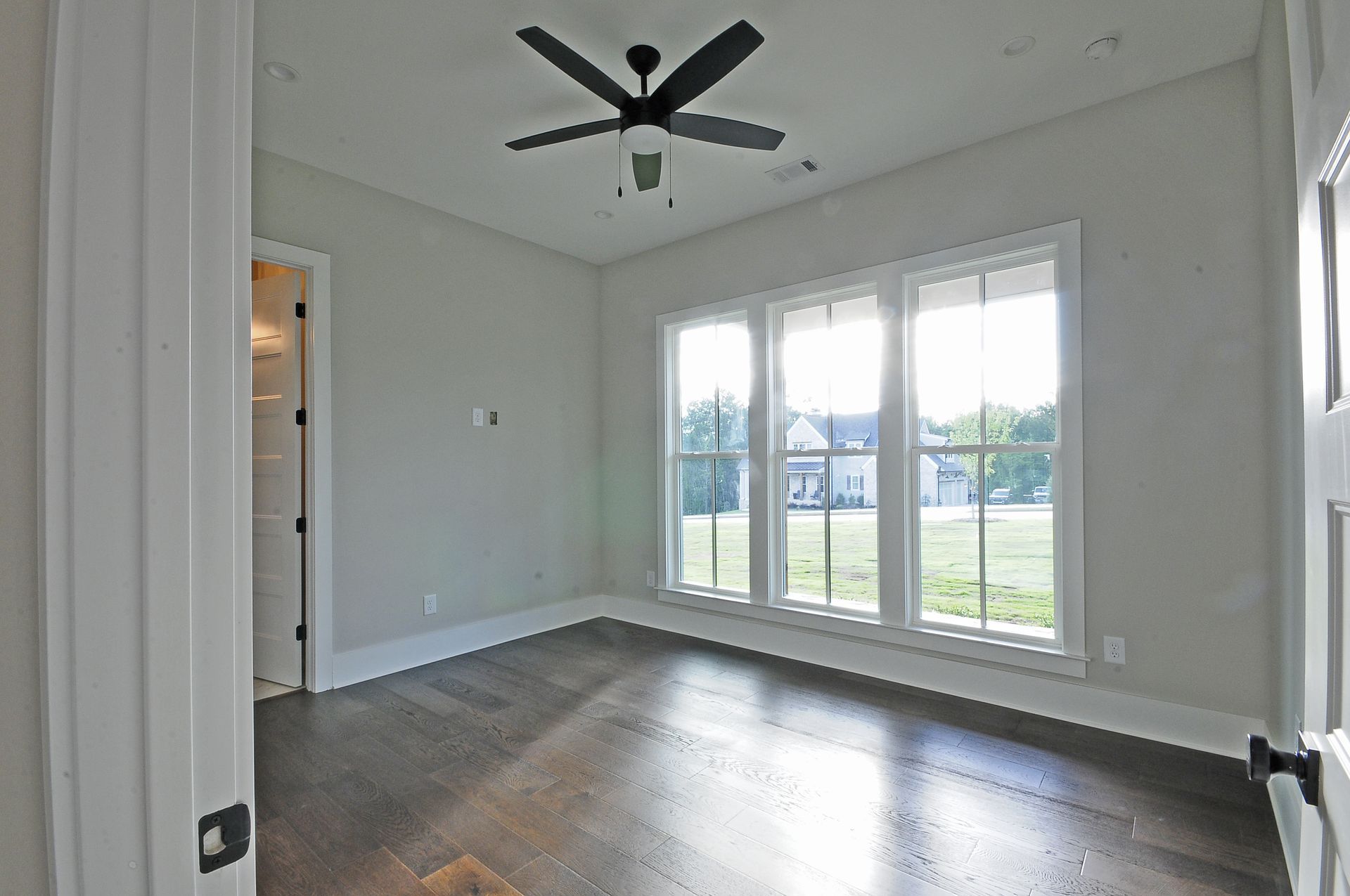 An empty room with a ceiling fan and lots of windows.