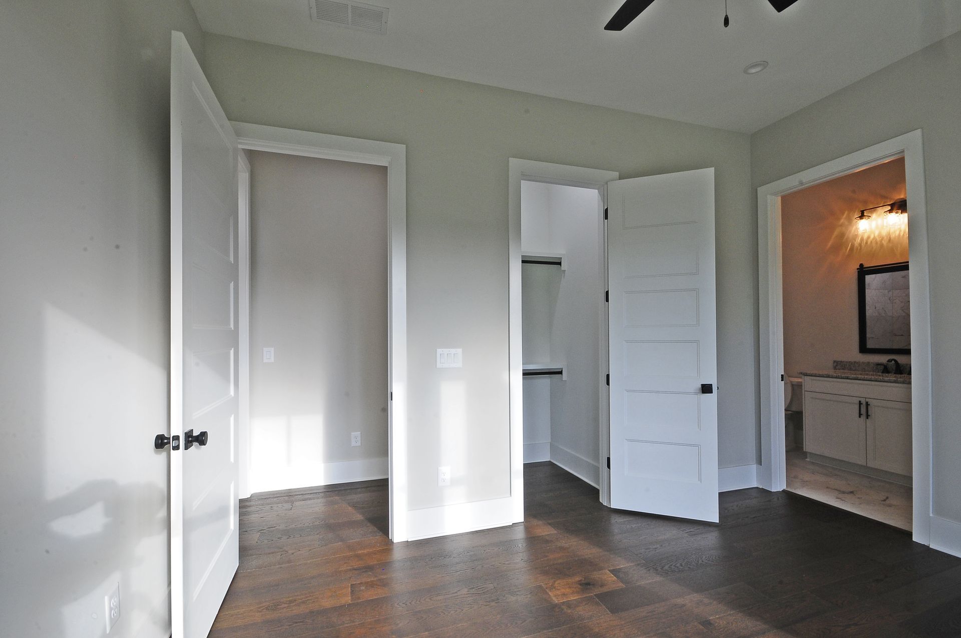 An empty room with white doors and a ceiling fan.