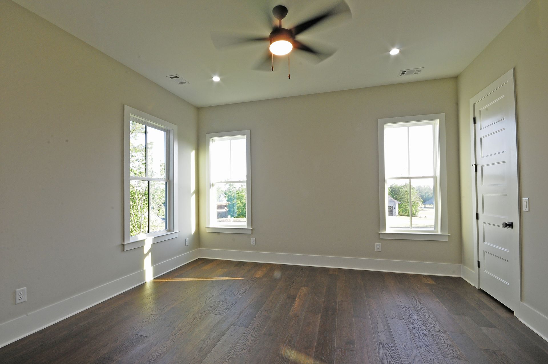 An empty room with hardwood floors and a ceiling fan.
