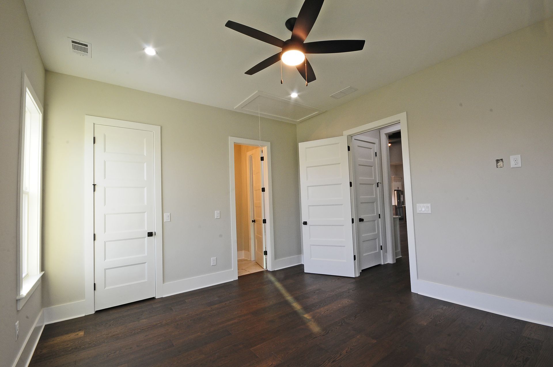 An empty bedroom with hardwood floors and a ceiling fan.