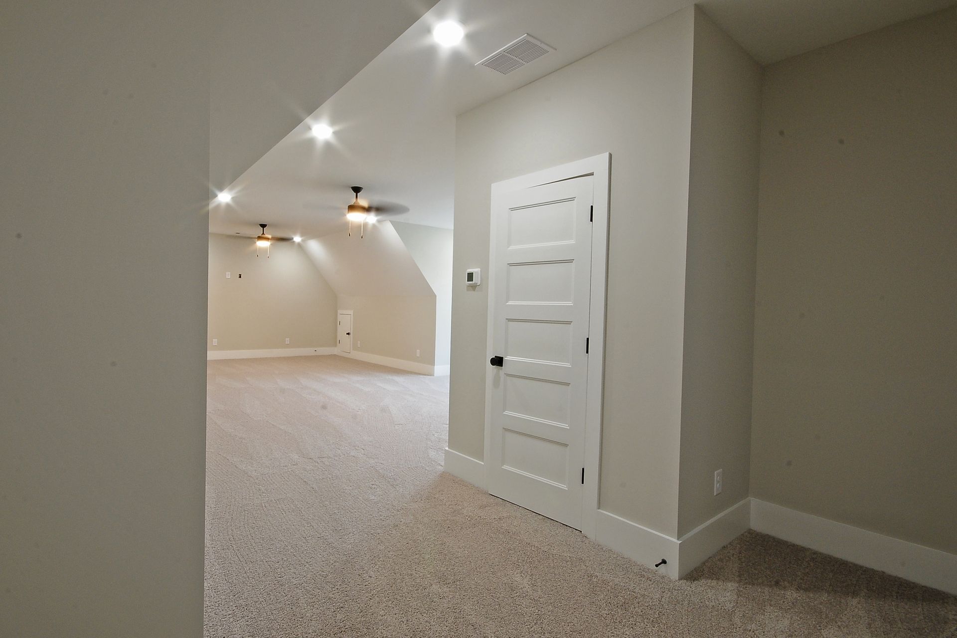 An empty room with a white door and a ceiling fan.