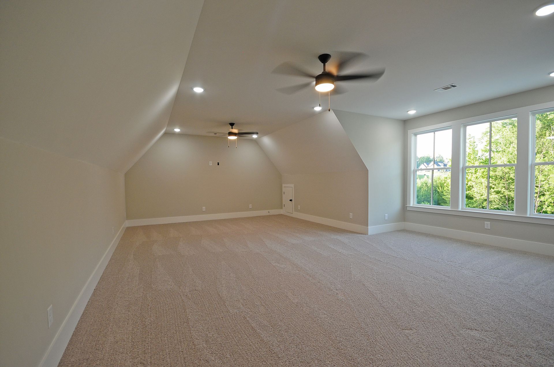 An empty room with a ceiling fan and a lot of windows