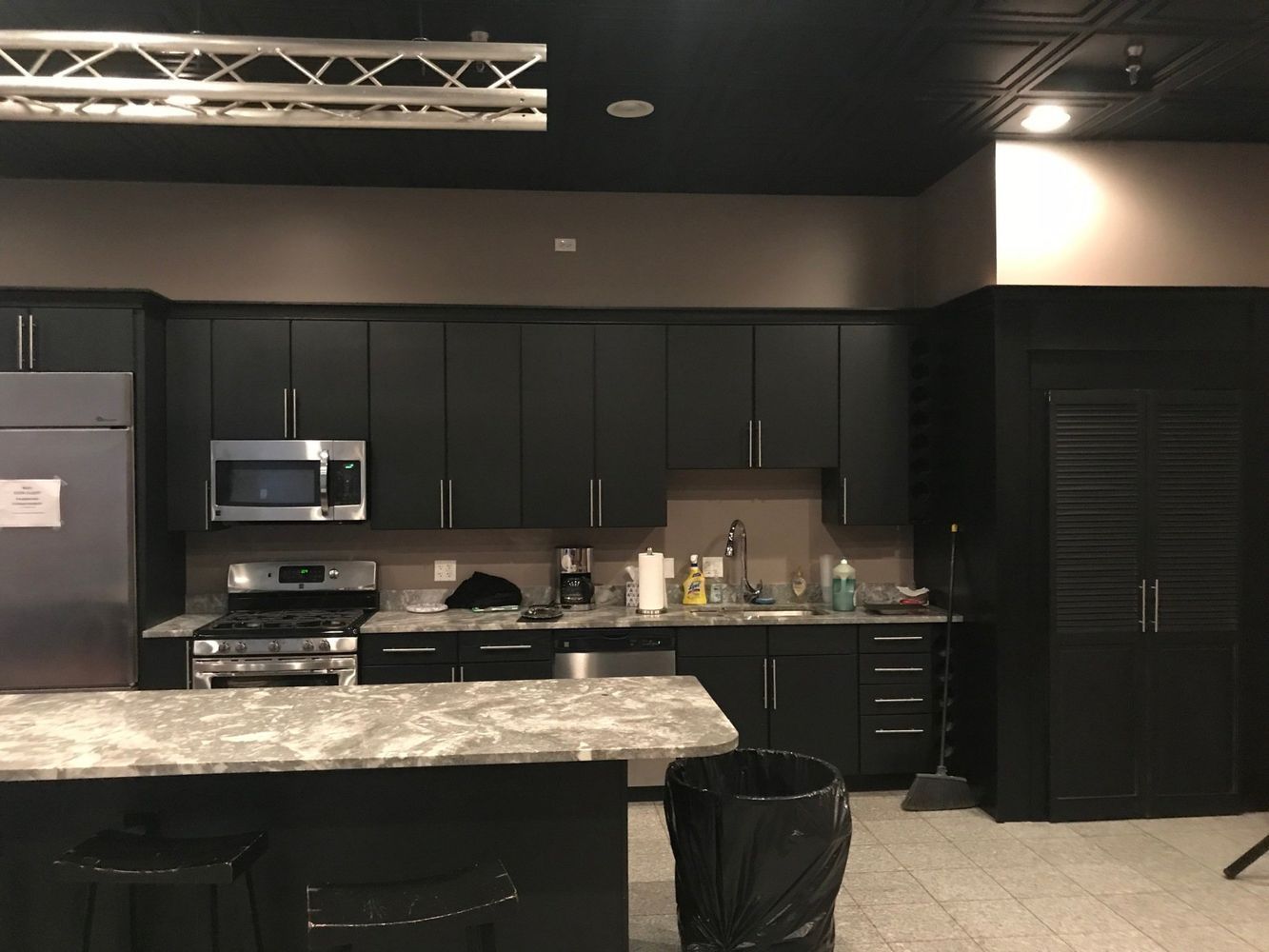 A kitchen with black cabinets and stainless steel appliances