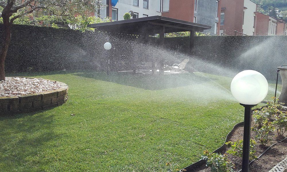 degli irrigatori che spruzzano acqua in un giardino con un gazebo