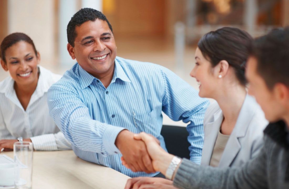 Un grupo de personas se dan la mano mientras están sentadas en una mesa.