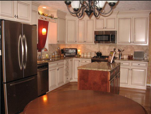 Kitchen with stainless steel appliances, cream cabinets, granite countertops, and a dark wooden island.