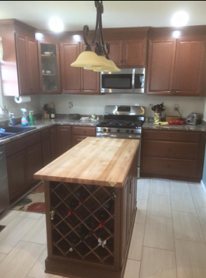 Kitchen with brown cabinets, stainless steel appliances, and an island with a wine rack.