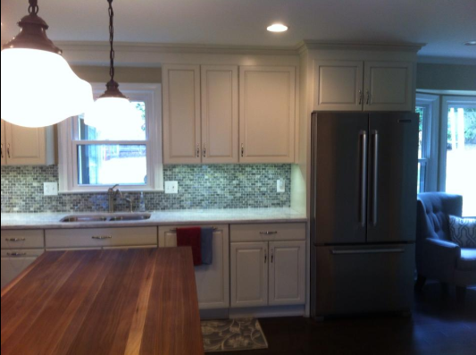 Kitchen with cream cabinets, stainless steel fridge, and a dark wooden countertop.