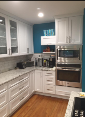 White kitchen cabinets, granite countertops, stainless steel appliances, and teal wall accent.